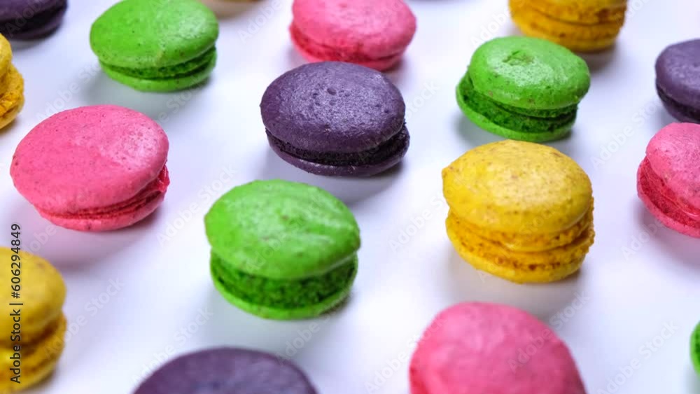 Rotating background of sweet macaroon cookies in different colors on a pink background Rotating background of sweet macaroon cookies in different colors on a pink background