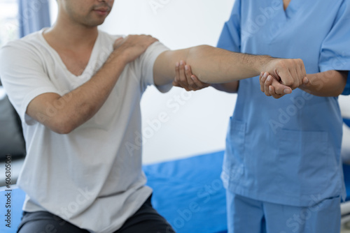 Physician or physiotherapist doing physiotherapy on shoulder, arm injury of male athlete patient stretching and exercise cause pain rehabilitation therapy, health insurance.