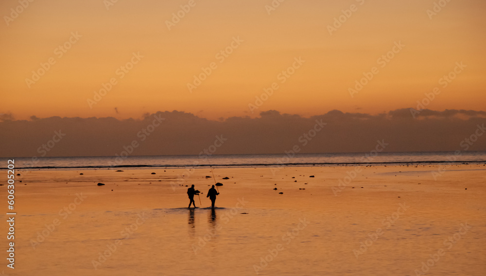 fishmen in the sea in the evening sunlight on the background of the sunset