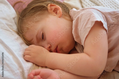 Peaceful adorable baby sleeping on his bed at home. Sleeping newborn baby concept. One year old baby girl sleeps peaceful at domestic room interior background. Serene dream. Cute Face Close Up
