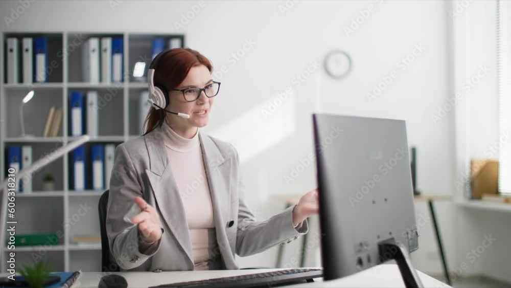 call center employee, charming woman in glasses talking to a client using a headset while sitting at computer in office call center employee, charming woman in glasses talking to a client using a headset while sitting at computer in office