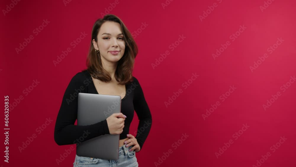 An attractive freelance woman with a laptop on a red background. Smiling model. The concept of a business person An attractive freelance woman with a laptop on a red background. Smiling model. The concept of a business person