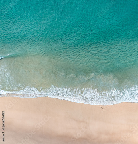 Aerial view of a beach scene with nice waves, blue water and warm sand 