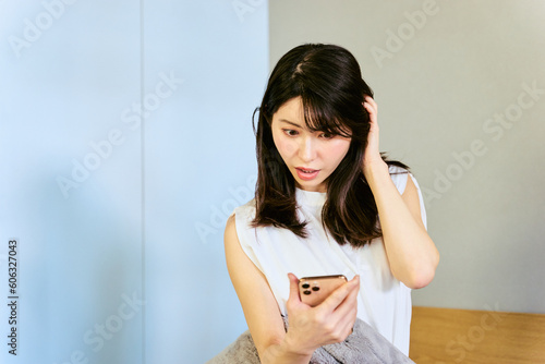 起床時にスマートフォンで時間を確認し寝坊し出勤時間に遅刻しそうな30代の1人暮らしの日本人の女性 photo