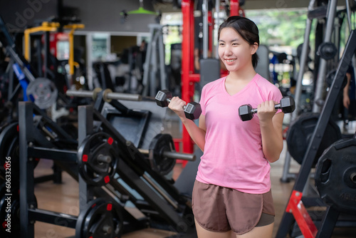 Asian women exercise arm muscles in the gym.Exercise concept for toning and losing weight to have a good figure. © Worranan