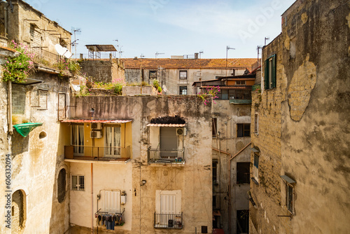 Fototapeta Naklejka Na Ścianę i Meble -  Facade in an inner courtyard in old town Centro storico of italian metropole Naples. Balconys and windows of typical residential building Palazzo in rotten, weathered condition,