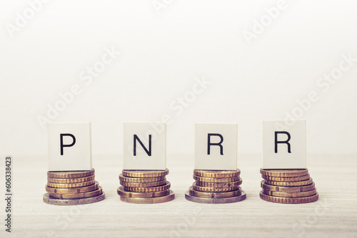 Stacks of coins with PNRR letters on white background. UE economy concept.