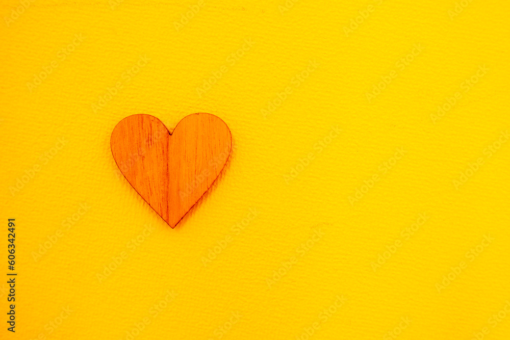 small wooden heart on a yellow background, horizontal small wooden heart on a yellow background, horizontal