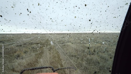 UTV driving fast along fence line on Montana prairie through muddy windshield