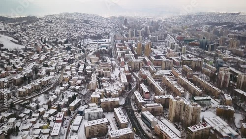 Aerial cinematic drone winter snowy streets and buildings downtown Sarajevo City center avaz twist Bosnia and Herzegovina cars and highway frozen landscape mid day slow pan up backward movement photo
