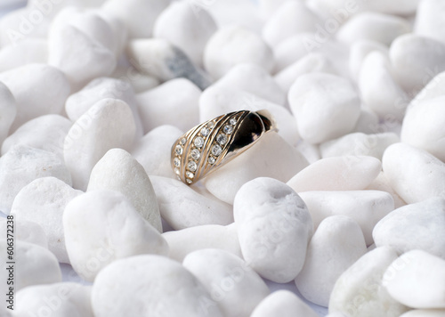 Golden ring with small stones on white pebbles
