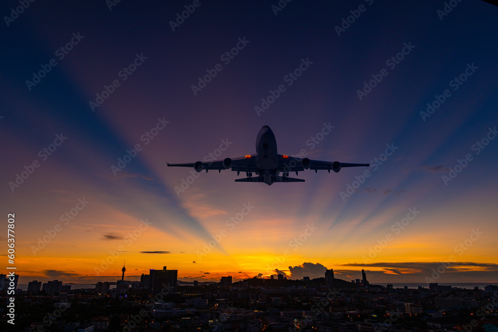 Airplane passenger cargo and commercial flying above silhouette city with twilight sun sky background