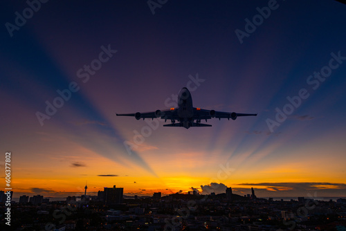 Airplane passenger cargo and commercial flying above silhouette city with twilight sun sky background