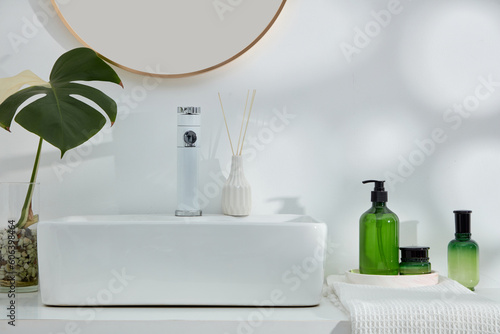 Several bath accessories placed on a cabinet with a monstera plant and a set of cosmetic container in green gradient color. Branding mockup