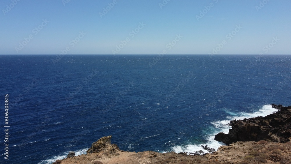 Aerial drone view of foamy waves crashing on a rocky coast on a sunny day in Tenerife Aerial drone view of foamy waves crashing on a rocky coast on a sunny day in Tenerife
