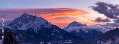 Beautiful panoramic shot of snowy mountains against a cloudy sky during the sunset