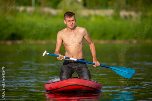 The guy swims on the SUP with an oar. Supsurfing on the lake. Board swimming. photo