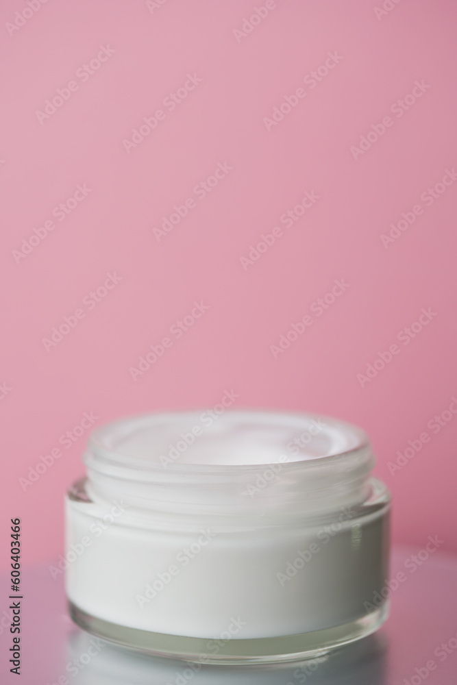 Glass jar with white face cream moisturiser on pink background. Glass jar with white face cream moisturiser on pink background.