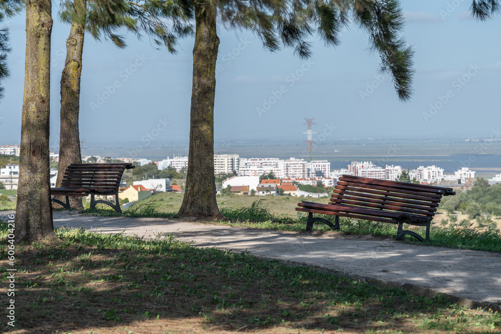 Obraz premium Path in the park with wooden benches on a background of the city of Loures, Portugal
