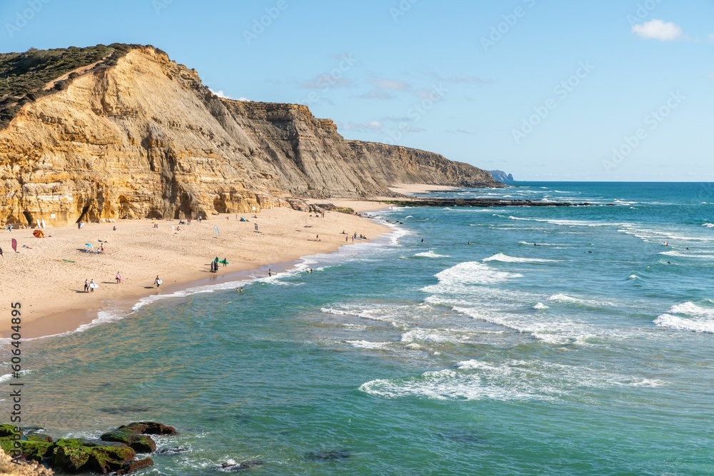 Scenic view of the Sao Juliao beach in Sintra,Portugal from a cliff with people sunbathing on shore