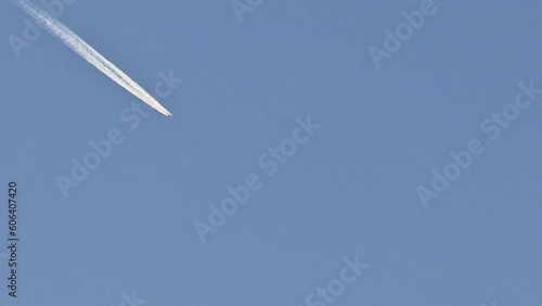 Airplane and its white trail against the blue sky photo
