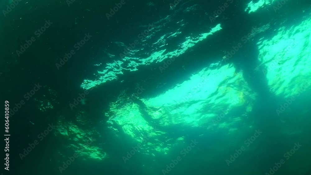 Sea pier, view from below. In the greenish water against the background of the undulating water surface, the Snake Island pier looks mysterious. Black Sea, Ukraine. Sea pier, view from below. In the greenish water against the background of the undulating water surface, the Snake Island pier looks mysterious. Black Sea, Ukraine.