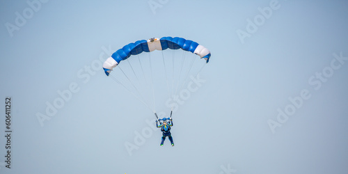 Skydiving. Flying parachutists against the background of the blue sky and mountains. Extreme sport and entertainment. photo
