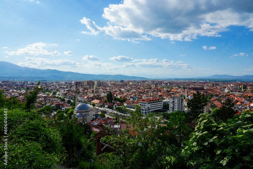 Aerial view of Prizren cityscape with lush green vegetation under blue cloudy sky in Kosovo