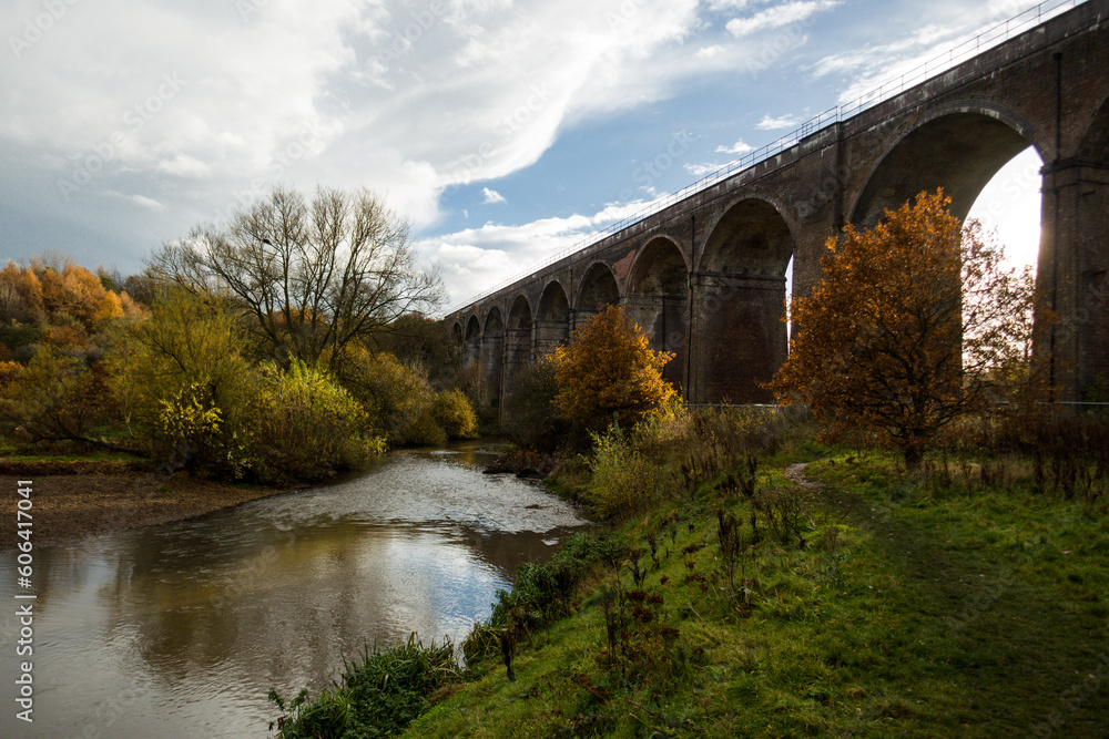 High arched stone bridge over a river with autumn trees in a park