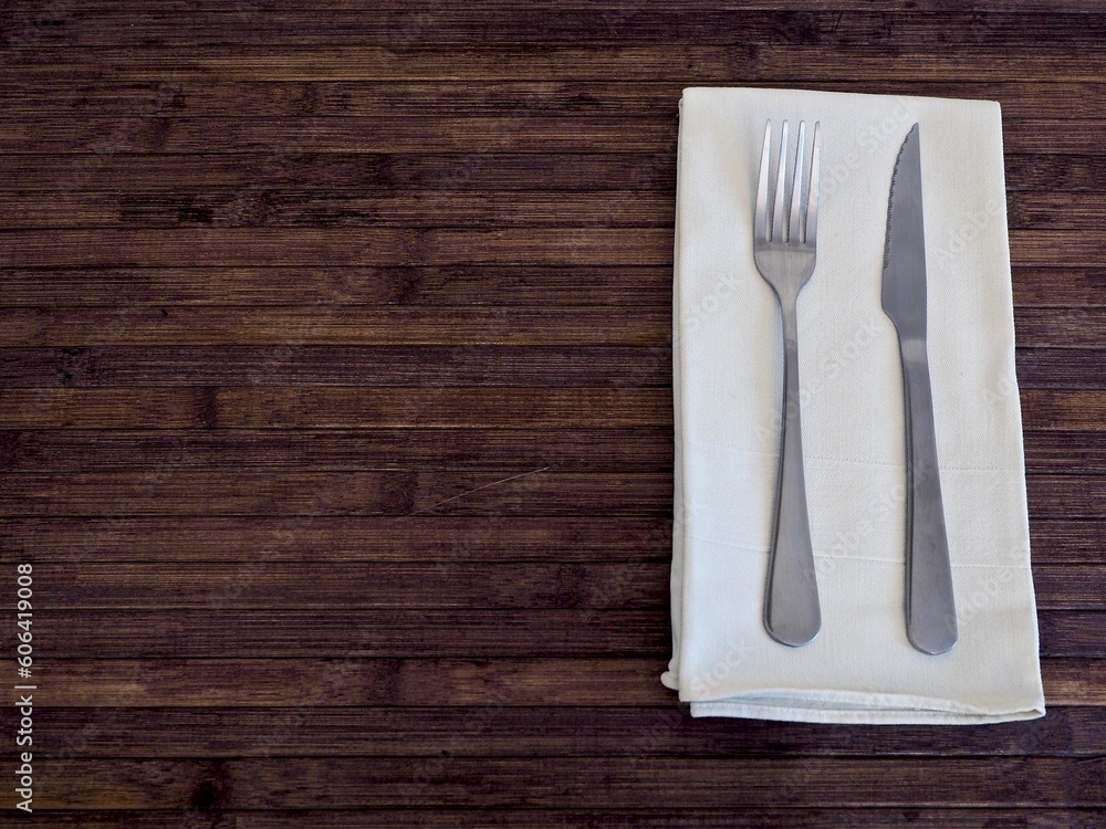 Top view shot of cutlery on white napkin on a wooden table with copy space Top view shot of cutlery on white napkin on a wooden table with copy space