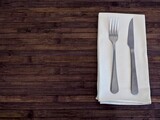 Top view shot of cutlery on white napkin on a wooden table with copy space