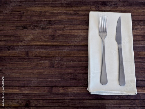 Top view shot of cutlery on white napkin on a wooden table with copy space