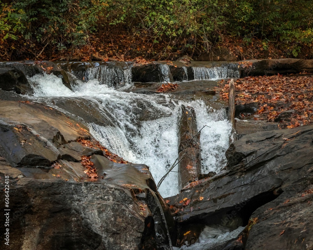 Small waterfall flowing down the rocks during the daytime in the fall Small waterfall flowing down the rocks during the daytime in the fall
