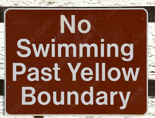 Closeup of a no swimming warning sign on a red board