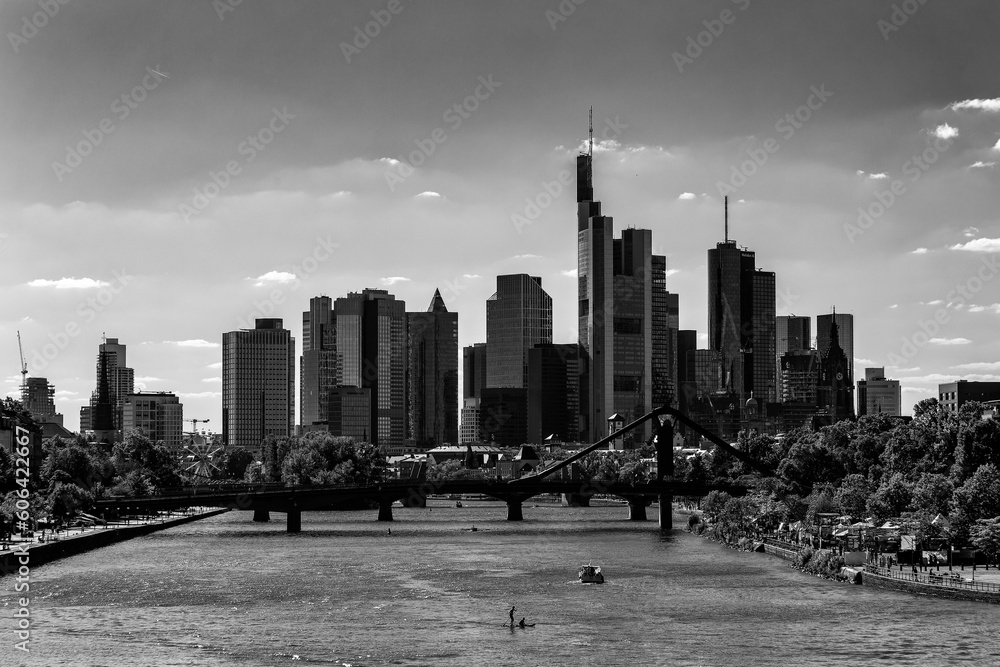 Grayscale beautiful view of a river with bridge and skyscrapers in a background