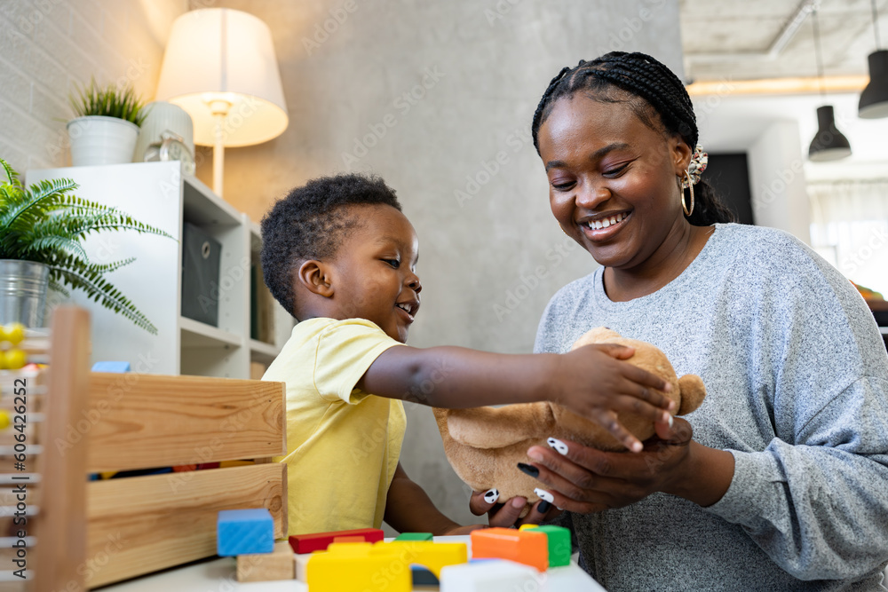 A cute little African child plays with colorful didactic educational toys. His proud mother supports him. Kindergarten teacher with child. A cute little African child plays with colorful didactic educational toys. His proud mother supports him. Kindergarten teacher with child.