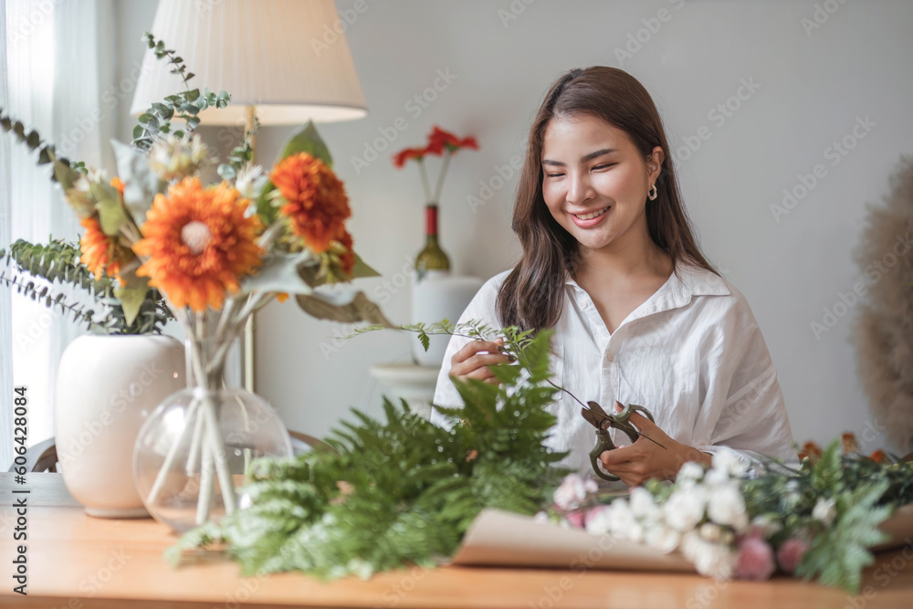 Attractive and happy young Asian woman enjoys arranging a vase with beautiful flowers in her minimal living room. Leisure and lifestyle concepts Attractive and happy young Asian woman enjoys arranging a vase with beautiful flowers in her minimal living room. Leisure and lifestyle concepts