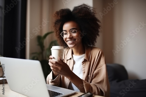 Afro woman seated holding a cup of coffee while teleworking