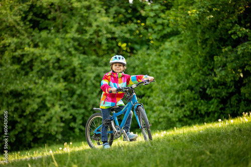 Happy kid boy, having fun in park with a bicycle on beautiful day. Active child wearing bike helmet