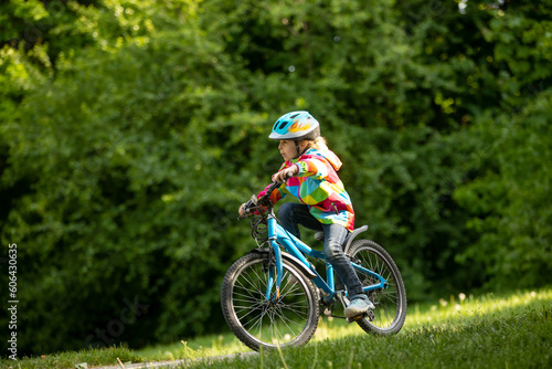 Happy kid boy, having fun in park with a bicycle on beautiful day. Active child wearing bike helmet