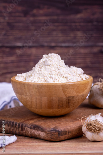 Garlic powder on wooden background. Dried ground garlic powder spices in wooden bowl. Close up