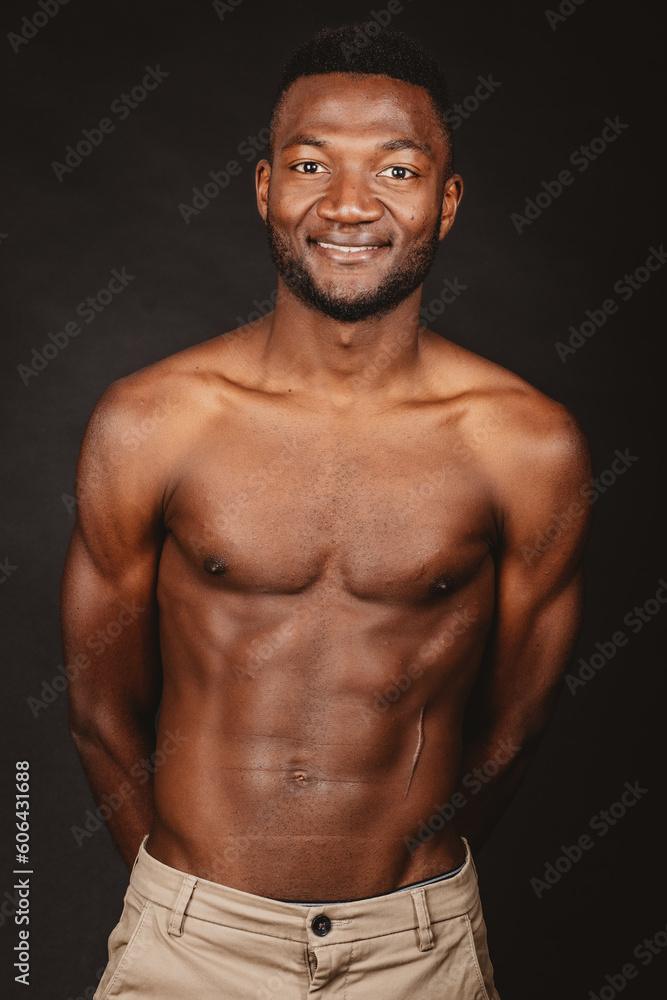 Portrait of a smiling African boy with bare chest in studio, isolated against a black background. Portrait of a smiling African boy with bare chest in studio, isolated against a black background.
