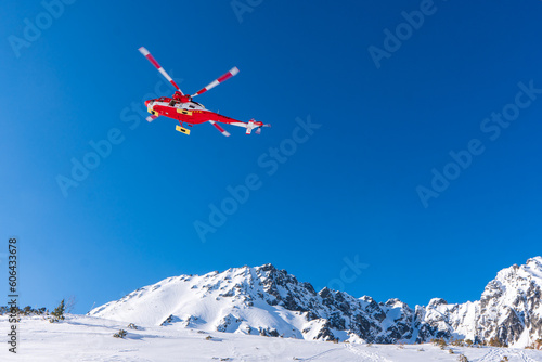 Fototapeta Naklejka Na Ścianę i Meble -  Red rescue helicopter moving in blue sky with blur propeller in winter mountains. Europe slovakia poland