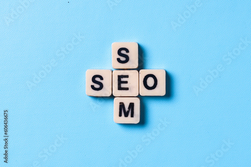 Wooden cubes with the word SEO and SEM isolated on blue background. Search Engine Marketing and Search Engine Optimization. 