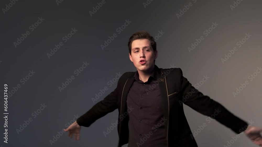 Excited young business manager man celebrating business success, promotion, professional achievement or awards, dancing alone against dark background Excited young business manager man celebrating business success, promotion, professional achievement or awards, dancing alone against dark background