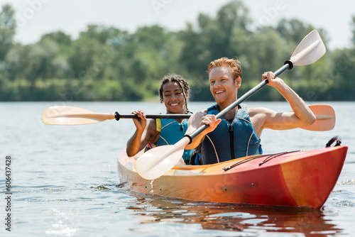 Bild auf Leinwand active redhead man and charming african american woman in life vests spending ti