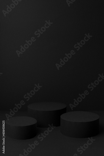 Abstract black stage with three cylinder podiums mockup for presentation cosmetic products, goods, advertising, design, text with soft gradient, in trendy exquisite simple style, vertical, copy space.