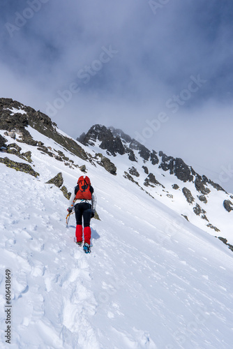 An alpinist climbing in winter alpine like landscape of High Tatras, Slovakia. Winter mountaineering in snow, ice and rock. Alpinism, high peaks and summits with snow and ice. © Martin