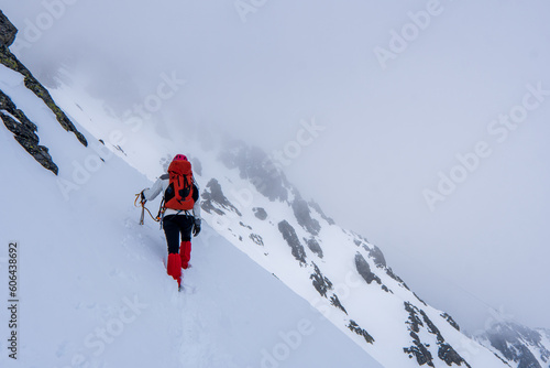 An alpinist climbing in winter alpine like landscape of High Tatras, Slovakia. Winter mountaineering in snow, ice and rock. Alpinism, high peaks and summits with snow and ice.