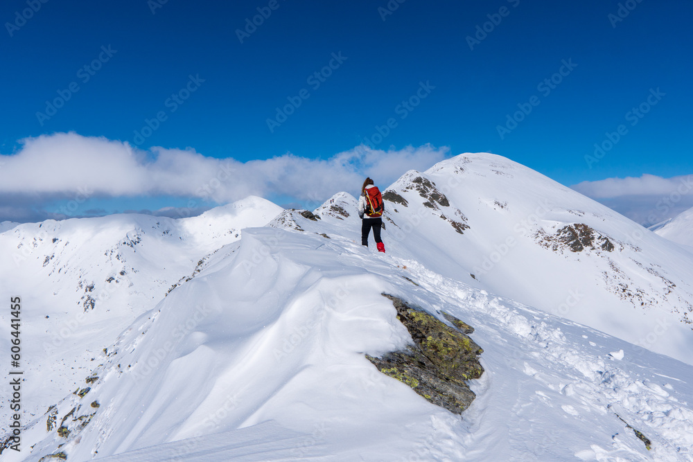 Active woman snow shoe hiking on a trail with scenic view on snow capped mountain peaks of West Tatras mountain in Slovakia, Europe. Julian Alps. Sunny winter day. Freedom.